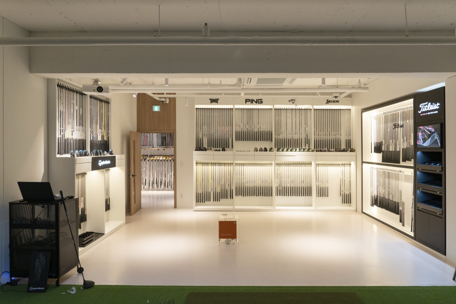TINO5 fitting studio — club wall with PXG, PING, Callaway, Srixon and Titleist, plus TrackMan
